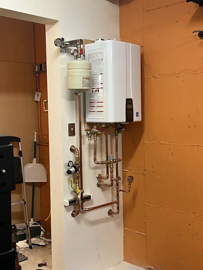 Plumbing technician inspecting water heater connections in West Union